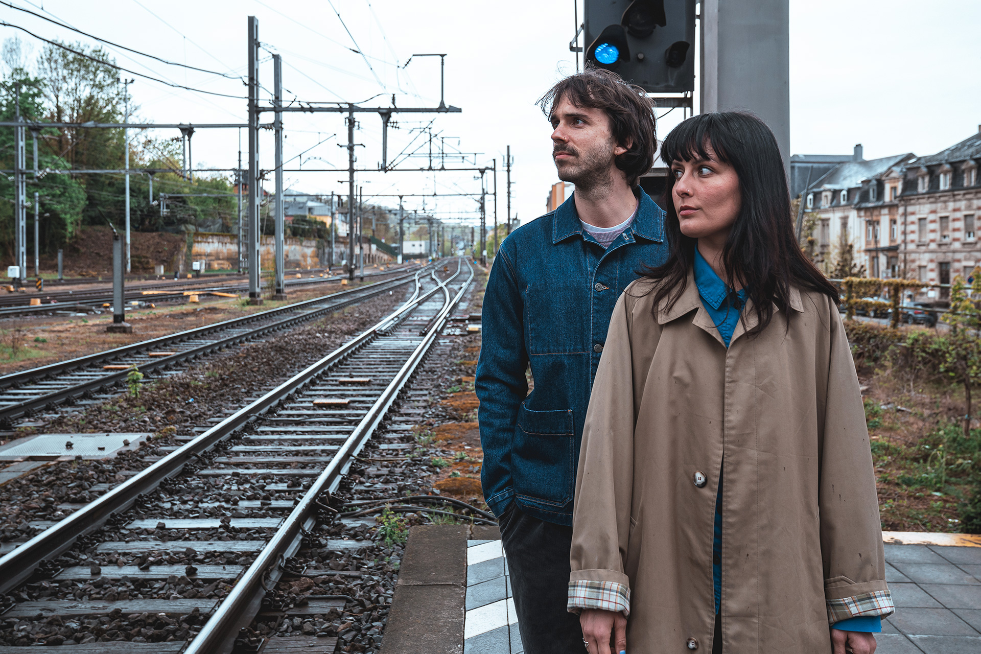 Un homme et une femme sont debout sur le quai d’une gare, posant face à la caméra.